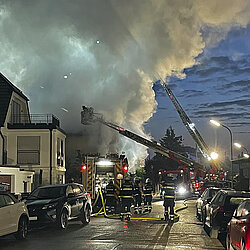 Brennendes Wohnhaus mit Rauchwolken und Löscharbeiten im Morgengrauen