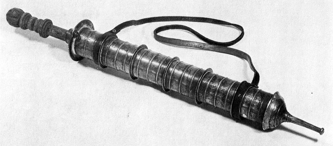 Historische Stockspritze aus Metall mit langem zylindrischem Körper und Schlaufe zum Tragen