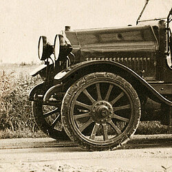 Historische Motorspritze von Saurer mit langer Leiter auf einem Dachgestell und offenem Fahrersitz auf Feldweg