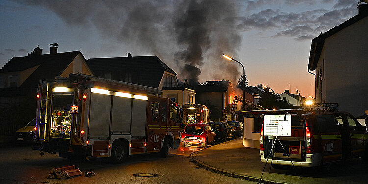 Brennendes Wohnhaus mit Rauchwolken und Löscharbeiten im Morgengrauen