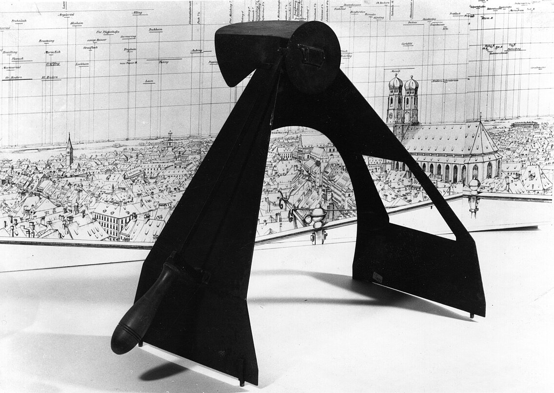 Schwarzes Pyroskop vor einer detaillierten Stadtplanzeichnung mit Gebäuden und einer Kirche im Hintergrund