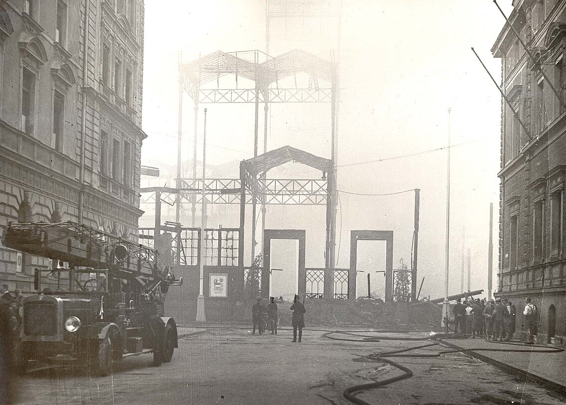 Der niedergebrannte Haupteingang des Glaspalastes von der Arcisstraße (heute Katharina-von-Bora-Straße) aus gesehen, wo vermutlich auch der Brand ausbrach, links ist die Drehleiter der Hauptwache zu sehen