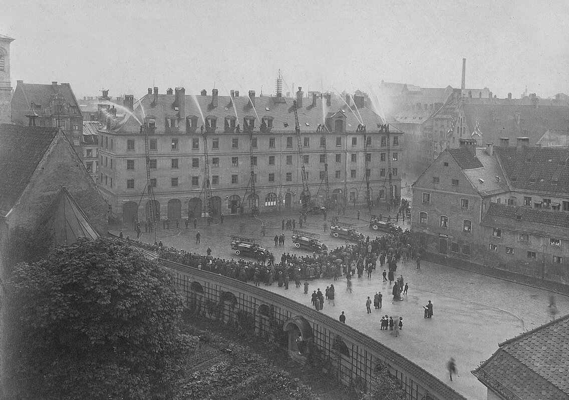Die neuen Fahrzeuge der Berufsfeuerwehr bei einer Übung am alten Feuerhaus, nun Stadtbauamt, vermutlich 1914 zur Präsentation der Leistungsfähigkeit des neuen Fuhrparks
