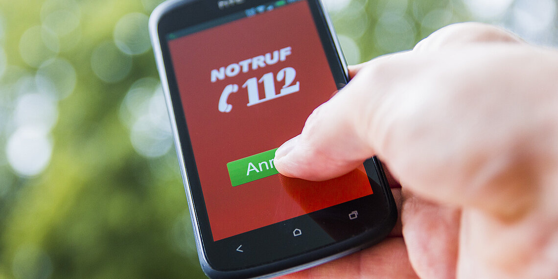 Hand tippt auf grünen Anrufbutton mit der Notrufnmmer 112 auf Smartphone