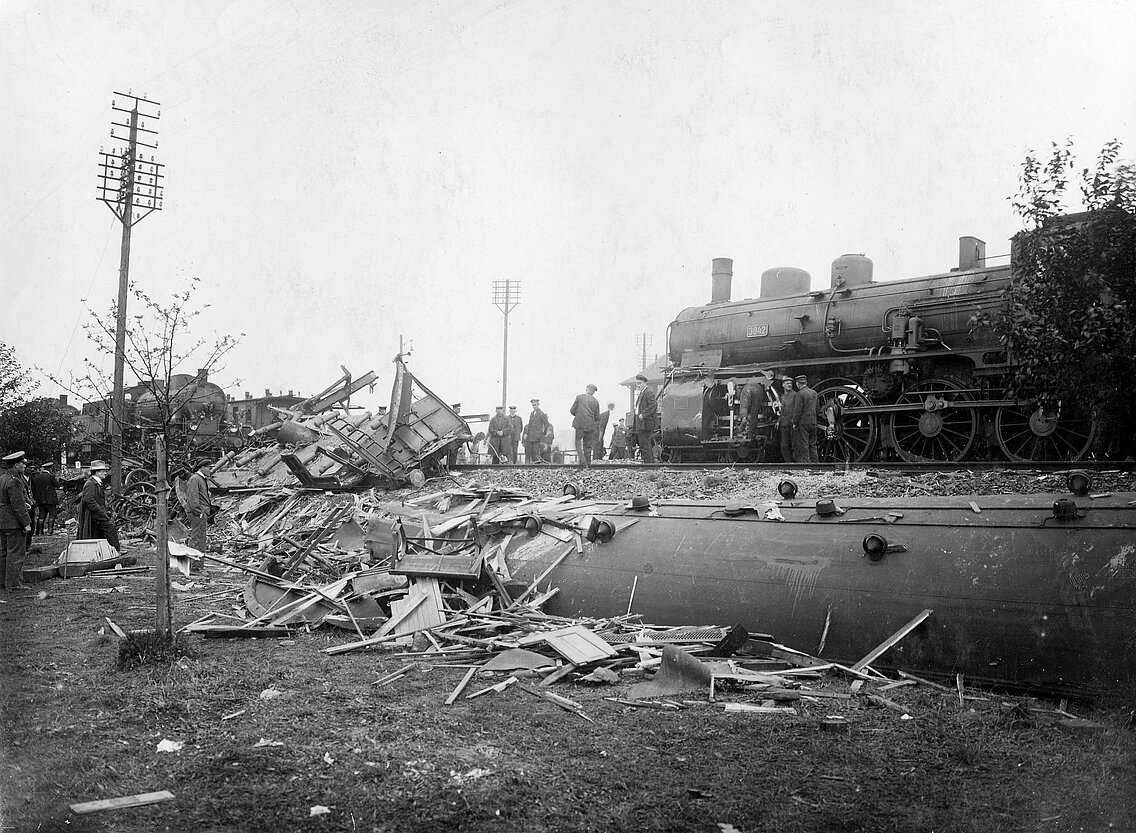 Die zerstörten Eisenbahnwagons im Graben neben der Strecke am Tag nach dem Unglück, die Dampfloks stehen für den Abtransport der noch auf den Gleisen befindlichen und fahrbereiten Wagons bereit 